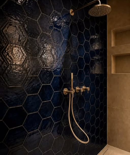 Douchewand met donkerblauwe zeshoekige tegels en messing kranen