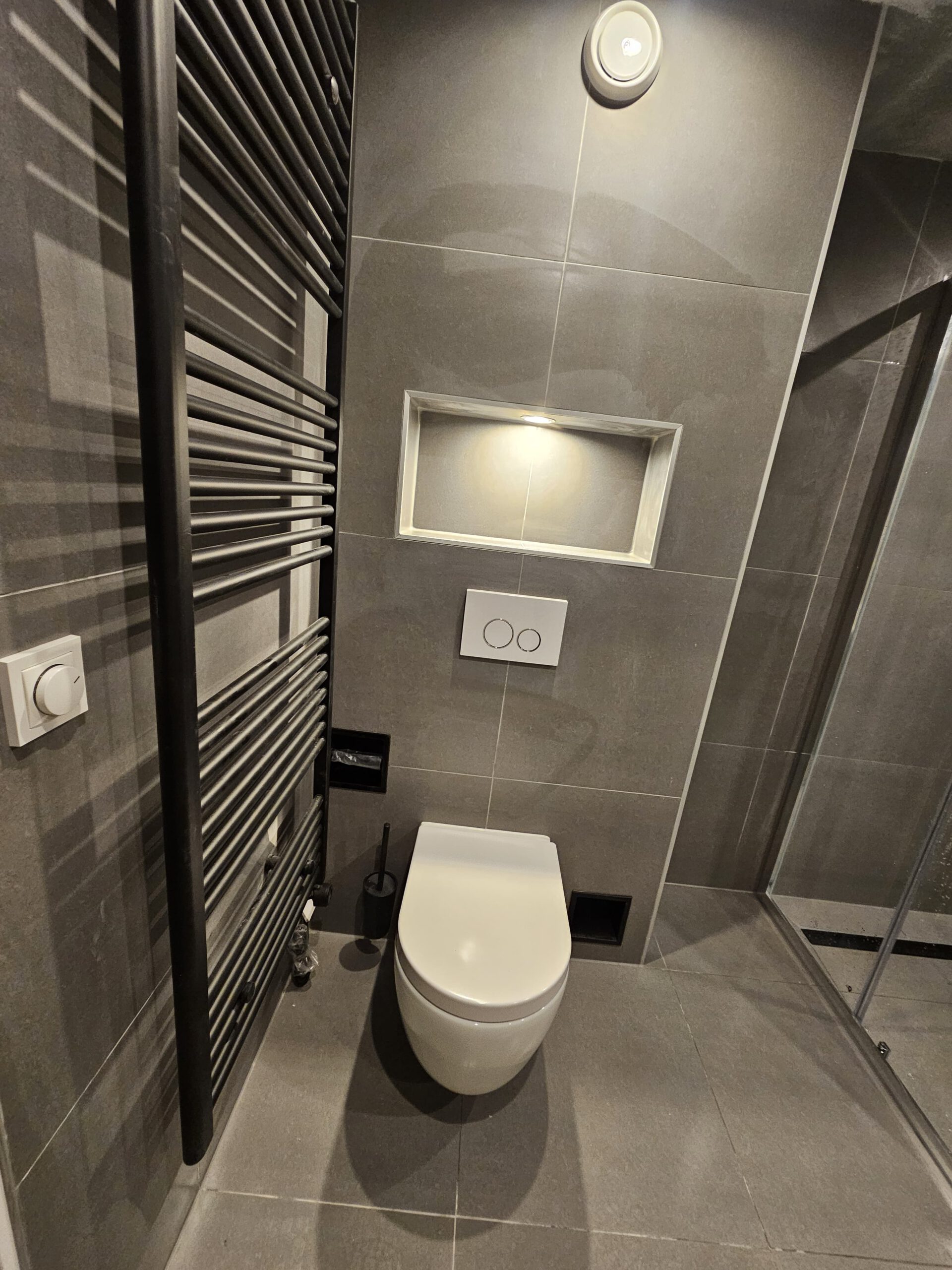 Toiletruimte in grijze tegels met verlichte nis